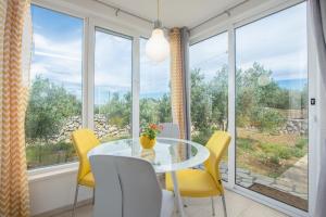 a dining room with a glass table and yellow chairs at House Lila Jacuzzy in Drvenik Mali