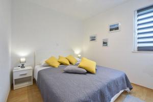 a white bedroom with a bed with yellow pillows at House Lila Jacuzzy in Drvenik Mali +38 photos