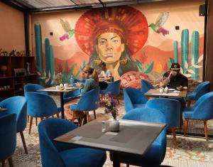 a restaurant with blue chairs and a mural of a woman at Way Kap Hostel Cusco in Cusco