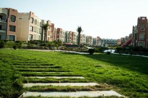 a field of grass with buildings in the background at شاليه in Marsa Alam