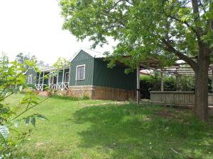 a green house with a tree in the yard at Pecan Cottage 2 in Machadodorp