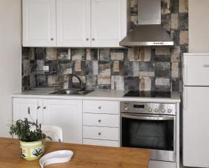 a kitchen with white cabinets and a sink and a stove at Petit house Vrachati in Vrachati