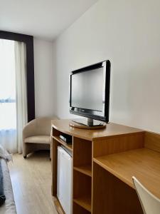 a living room with a television on a wooden desk at Flat 609 - Comfort Hotel Taguatinga - Particular in Brasília