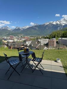 a table and chairs on a patio with a view of mountains at Chez Leny in Monthey