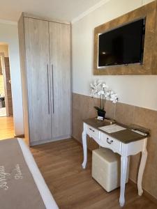 a bedroom with a white desk with a television on a wall at angela studios in Paleokastritsa