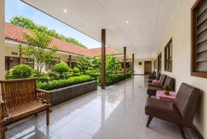 a hallway with benches and plants in a building at Hotel Budi Famili Budget Syariah in Ciamis