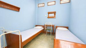 a room with two beds and a chair in it at Hotel Budi Famili Budget Syariah in Ciamis
