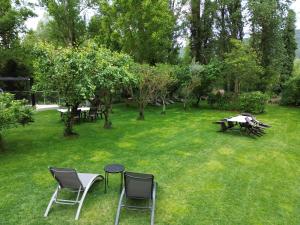 a yard with chairs and a table in the grass at Apartamentos Ordesa Ainsa in Aínsa