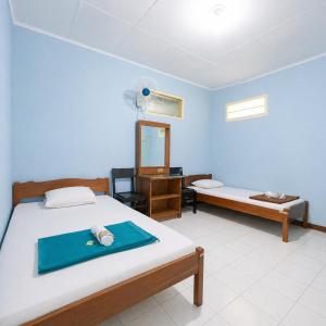 a bedroom with two beds and a desk and a mirror at Hotel Budi Famili Budget Syariah in Ciamis