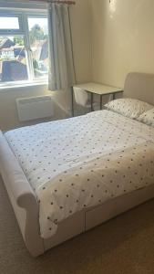 a white bed in a room with a table and a window at Edney Court in Reading