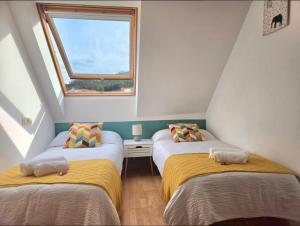 two twin beds in a room with a window at Ático Formoso in Cee