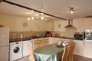 a kitchen with a table and chairs and a kitchen with white cabinets at Bakers Mill Holiday Cottages in Beaminster