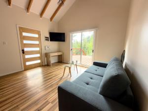 a living room with a blue couch and a wooden floor at Arriendo casa Caburgua Pucón in Caburgua
