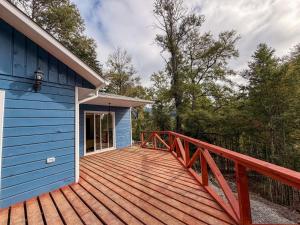 a large wooden deck next to a blue building at Arriendo casa Caburgua Pucón in Caburgua