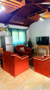 a living room with red furniture and a flat screen tv at Bambito´s Café & Hostel in Cerro Punta