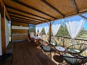 a porch with chairs and a table on a deck at Mobile home Magdalena in Pirovac
