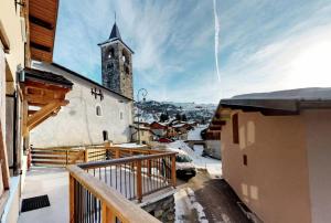 a church with a clock tower in the snow at Chalet De Manou - Chalet individuel rénové pour 12 personnes avec sauna dans les 3 Vallées MAE-3694 in Saint-Martin-de-Belleville