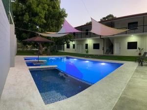 a swimming pool in front of a house at Churros Apartahotel in La Libertad