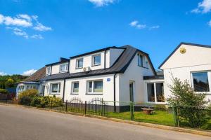 a white house with a black roof on a street at New apartment in Wise ka in Wisełka