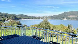 a balcony with a table and chairs and a view of a river at The Cliffs - ArealongaBeach in O Vicedo