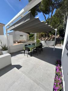 a patio with a green table and chairs under an umbrella at Casa Roca Maura in L'Estartit