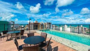 a balcony with tables and chairs and a swimming pool at Move Tambaú Genius Flats in João Pessoa