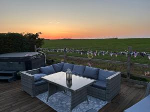 a patio with a couch and a table and a grill at Beautiful Rural Holiday Chalet With Hot tub and Igloo cinema in Lincolnshire