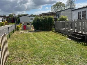 a yard with a fence and a bench in the grass at Camping le petit RIO in Noyelles-sur-Mer