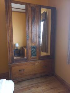 a large wooden cabinet with a mirror in a bedroom at Pecan Cottage Three in Machadodorp