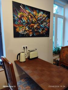 a table with a toaster and a painting on the wall at Gîte "fils de laine" Piscine chauffée interieure et Sauna ouverts toute l'année in Celles-sur-Plaine