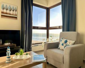 a living room with a chair and a table and a window at Face a l'océan, vue panoramique, 3 min a pied de la plage, Praia da areia branca in Praia da Areia Branca