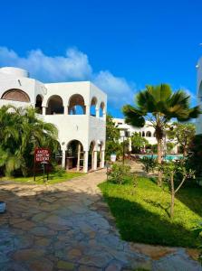 a white building with a palm tree in front of it at Studio Leliya in Malindi