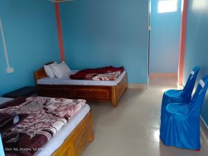 a bedroom with two beds and a blue wall at Chamling Retreat in Kalimpong