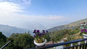 a vase with purple flowers on a balcony with mountains at Chamling Retreat in Kalimpong +15 photos