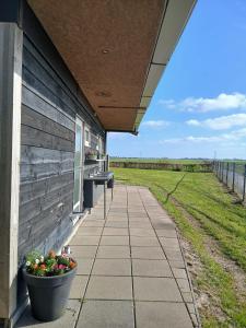 a porch with benches and flowers on the side of a building at Camping de Koaipleats in Akkerwoude