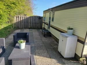 a patio with two potted plants next to a trailer at Camping de Koaipleats in Akkerwoude