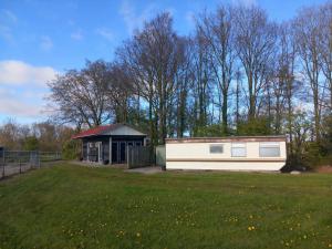 a small building in a field next to a park at Camping de Koaipleats in Akkerwoude