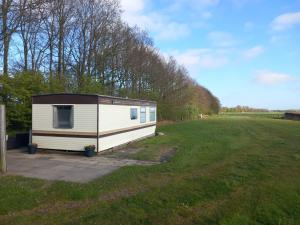 a small white trailer in a grass field at Camping de Koaipleats in Akkerwoude