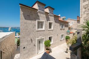 a large brick building with white windows and plants at Villa Marina Hvar in Hvar