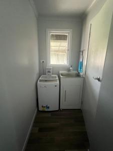a small kitchen with a sink and a washing machine at Marvellous on Maggie in Invercargill +22 photos