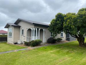 a small house with a tree in a yard at Marvellous on Maggie in Invercargill