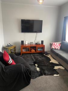 a living room with a couch and a flat screen tv at Marvellous on Maggie in Invercargill