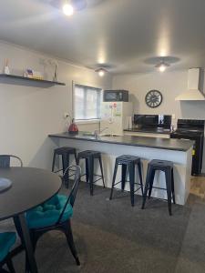 a kitchen with a counter and some chairs and a table at Marvellous on Maggie in Invercargill