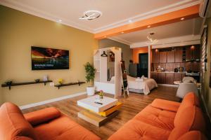 a living room with an orange couch and a bed at Tirana SkyView in Tirana
