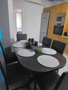 a black dining room table with chairs and a kitchen at Rosemary Guesthouse in Kavála