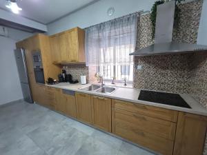a kitchen with wooden cabinets and a sink and a window at Rosemary Guesthouse in Kavála