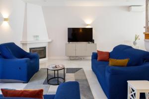 a living room with two blue chairs and a tv at Sun & Salt Villa in Alvor