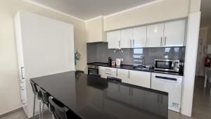 a kitchen with white cabinets and a black counter top at Face a l'océan, vue panoramique, 3 min a pied de la plage, Praia da areia branca in Praia da Areia Branca +22 photos