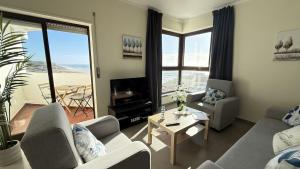 a living room with couches and a view of the ocean at Face a l'océan, vue panoramique, 3 min a pied de la plage, Praia da areia branca in Praia da Areia Branca