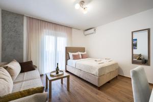 a white bedroom with a bed and a couch at Hillside Apartments in Bečići